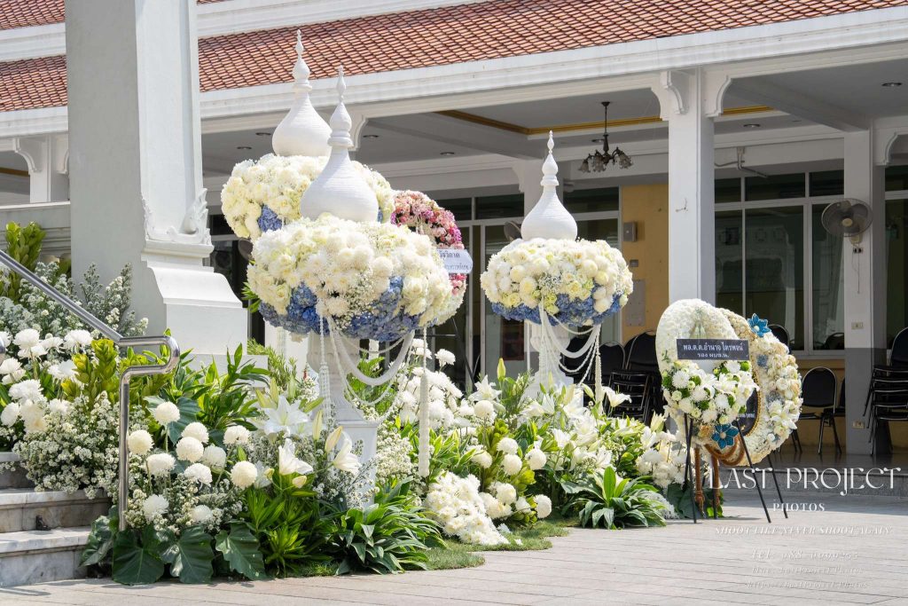 การจัดดอกไม้หน้าเมรุและพวงหรีดโทนสีขาวฟ้าในพิธีฌาปนกิจ วัดไทย Funeral flower decoration and wreaths in white and blue tones at the crematorium in a Thai Buddhist temple