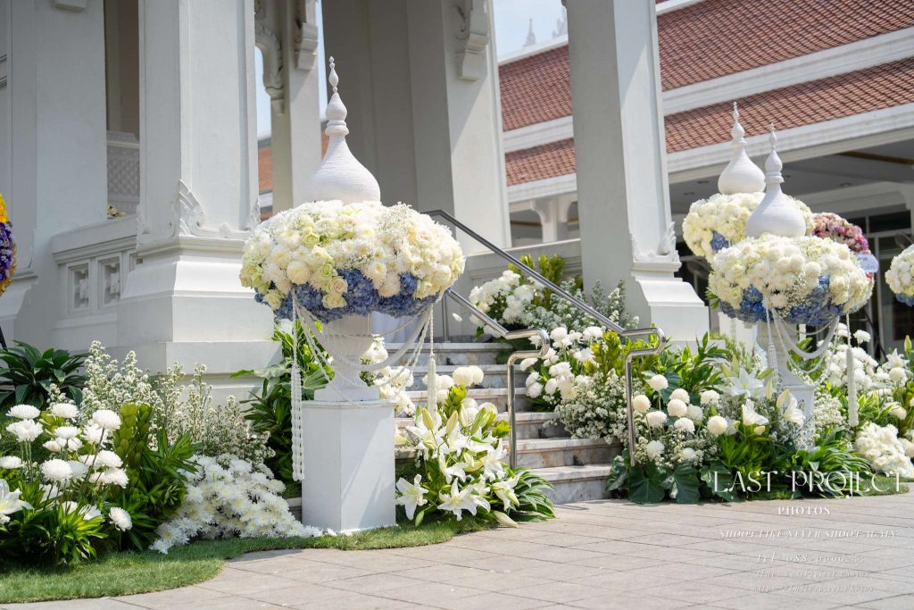 ภาพถ่ายการตกแต่งดอกไม้สีขาวและสีฟ้าหน้าบันไดเมรุในพิธีฌาปนกิจศพแบบไทย Professional funeral photography of white and blue floral decorations adorning the crematorium stairs in a Thai Buddhist cremation ceremony