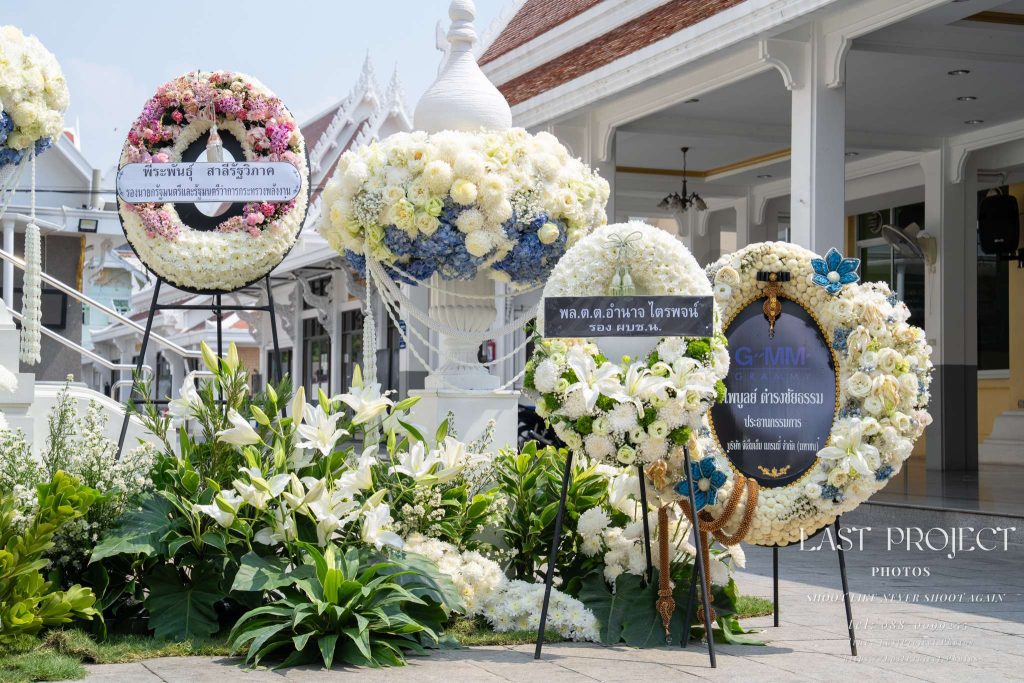 พวงหรีดดอกไม้สดแสดงความอาลัยประดับตกแต่งรอบเมรุในพิธีฌาปนกิจศพ ณ วัดไทย Fresh condolence flower wreaths elegantly arranged near the crematorium at a Thai Buddhist funeral ceremony