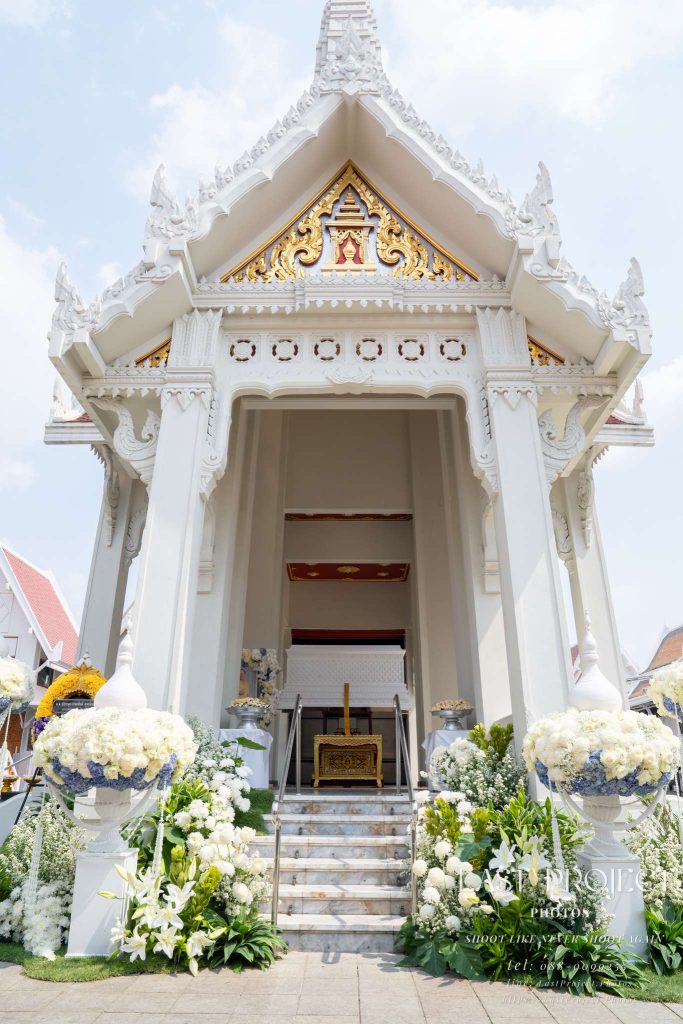 ภาพถ่ายพิธีฌาปนกิจและเมรุสีขาวประดับดอกไม้ ณ วัดเทพศิรินทราวาส กรุงเทพมหานคร A vertical view of a traditional white crematorium decorated with funeral flowers at Wat Debsirindrawas in Bangkok, Thailand