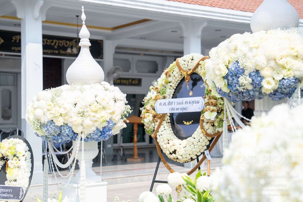 พวงหรีดและพุ่มดอกไม้ประดับตกแต่งบริเวณหน้าเมรุในพิธีฌาปนกิจศพ วัดไทย Funeral wreaths and elegant floral decorations in front of the crematorium during a traditional Thai Buddhist cremation ceremony.