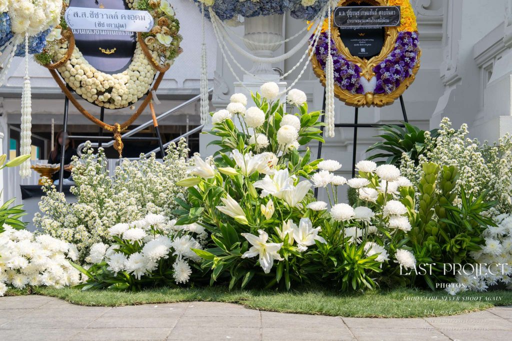 การจัดตกแต่งดอกไม้สดหน้าเมรุและพวงหรีดในพิธีฌาปนกิจศพ ณ วัดไทย Fresh funeral floral arrangements and wreaths around the crematorium during a Thai Buddhist cremation ceremony