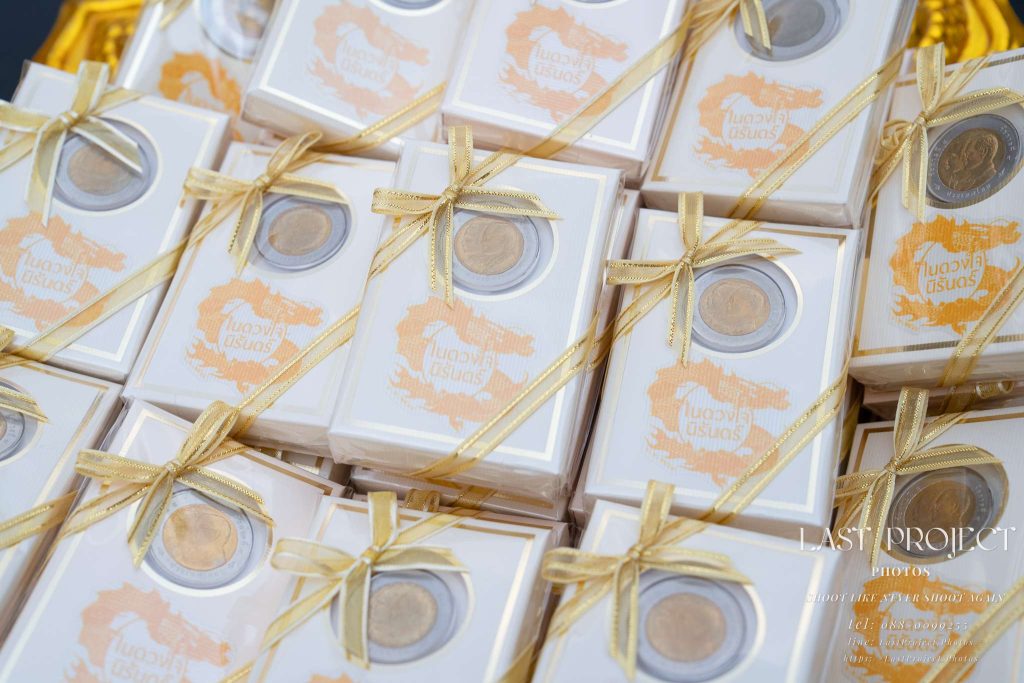 ของชำร่วยงานศพเหรียญกษาปณ์ที่ระลึก 10 บาท ผูกโบสีทองจัดวางบนพานในพิธีฌาปนกิจ Memorial 10-baht coin souvenir gift boxes with gold ribbons on a tray at a Thai Buddhist funeral ceremony