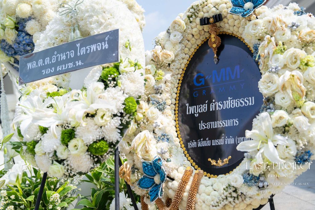 พวงหรีดดอกไม้สดสีขาวแสดงความอาลัยในพิธีฌาปนกิจ ณ วัดไทย White fresh flower funeral wreaths for condolence at a Thai temple cremation ceremony.