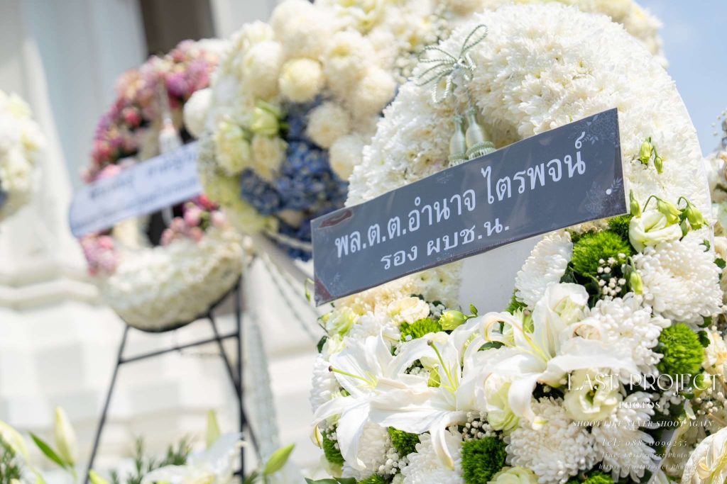 พวงหรีดดอกไม้สดสีขาวแสดงความอาลัยในพิธีฌาปนกิจ ณ วัดไทย White fresh flower funeral wreaths for condolence at a Thai temple cremation ceremony.