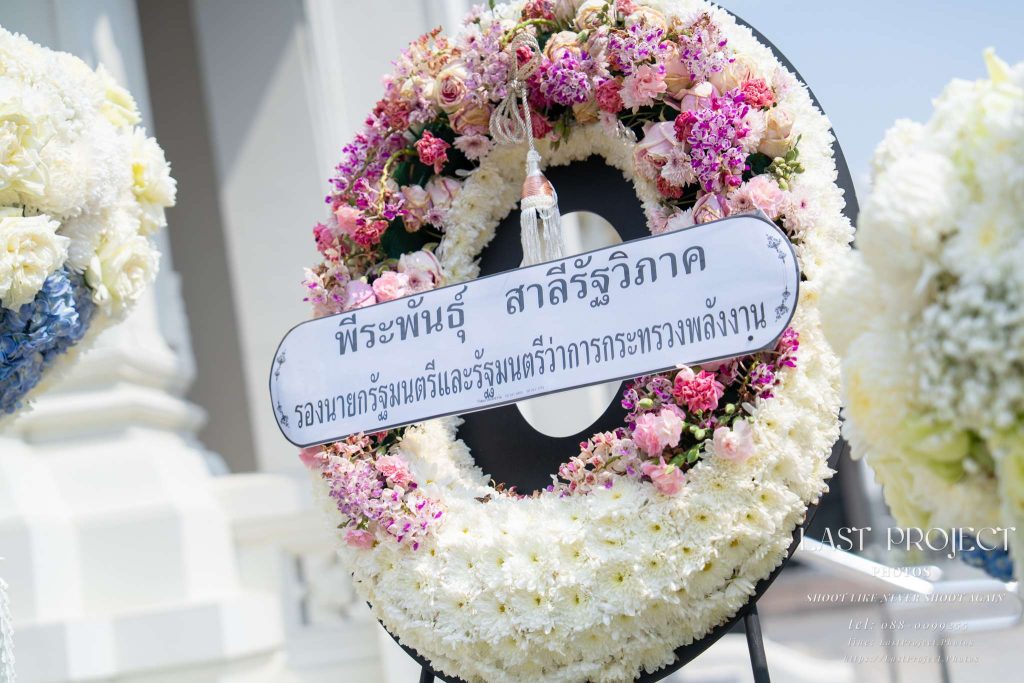 พวงหรีดดอกไม้สดสีขาวแสดงความอาลัยในพิธีฌาปนกิจ ณ วัดไทย White fresh flower funeral wreaths for condolence at a Thai temple cremation ceremony.