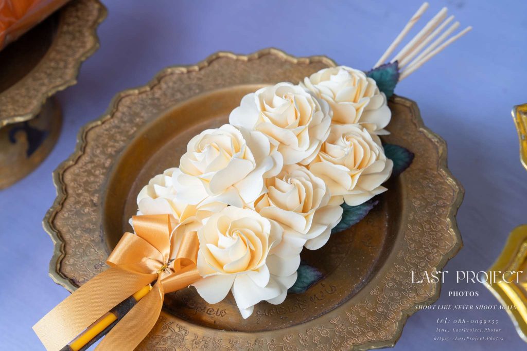 ช่อดอกไม้จันทน์สำหรับประธานในพิธีฌาปนกิจวางบนพานทองเหลือง An ornate sandalwood flower bouquet on a brass pedestal tray for the presiding guest at a Thai funeral cremation ceremony