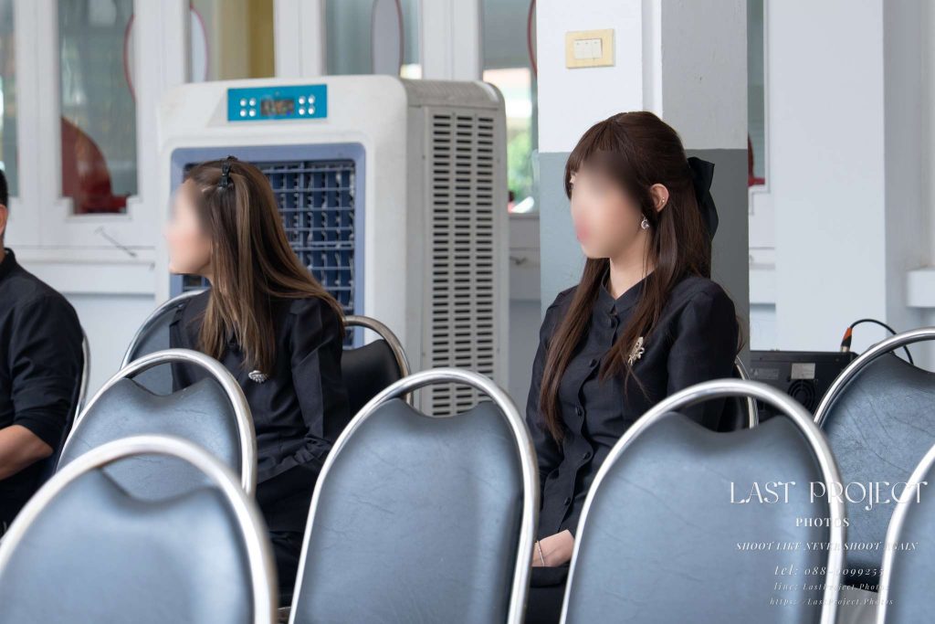 แขกผู้หญิงสวมชุดดำไว้ทุกข์นั่งร่วมพิธีฌาปนกิจ Female guests wearing black mourning attire attending a Buddhist funeral ceremony