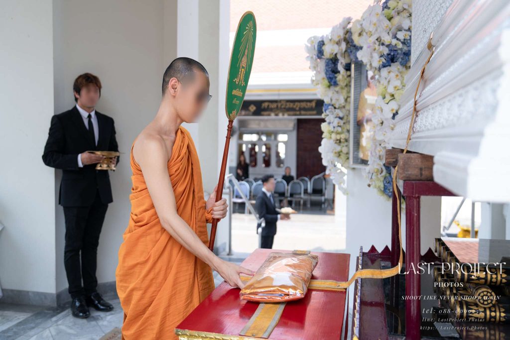 พระสงฆ์กำลังประกอบพิธีพิจารณาผ้าไตรบังสุกุลหน้าจิตกาธานในพิธีฌาปนกิจศพตามประเพณีไทย Buddhist monk performing the Bangsukula robe reflection ceremony at the cremation pyre in a traditional Thai funeral