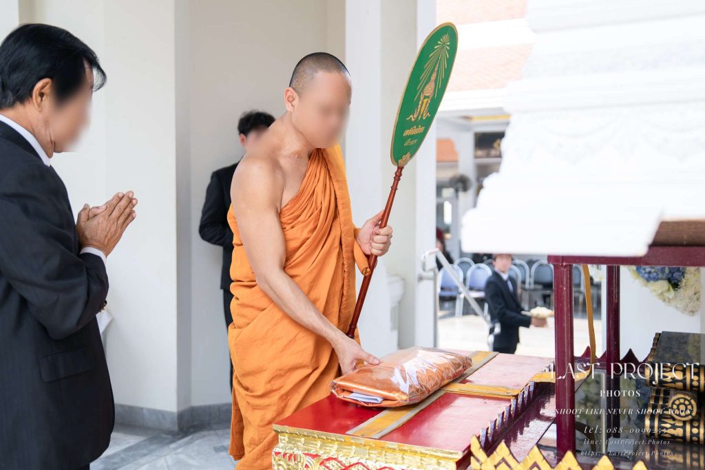 พระสงฆ์ทำพิธีพิจารณาผ้าไตรบังสุกุลบนเมรุในงานฌาปนกิจศพ A Buddhist monk performing the Bangsukun robe contemplation ritual during a Thai cremation ceremony at a temple