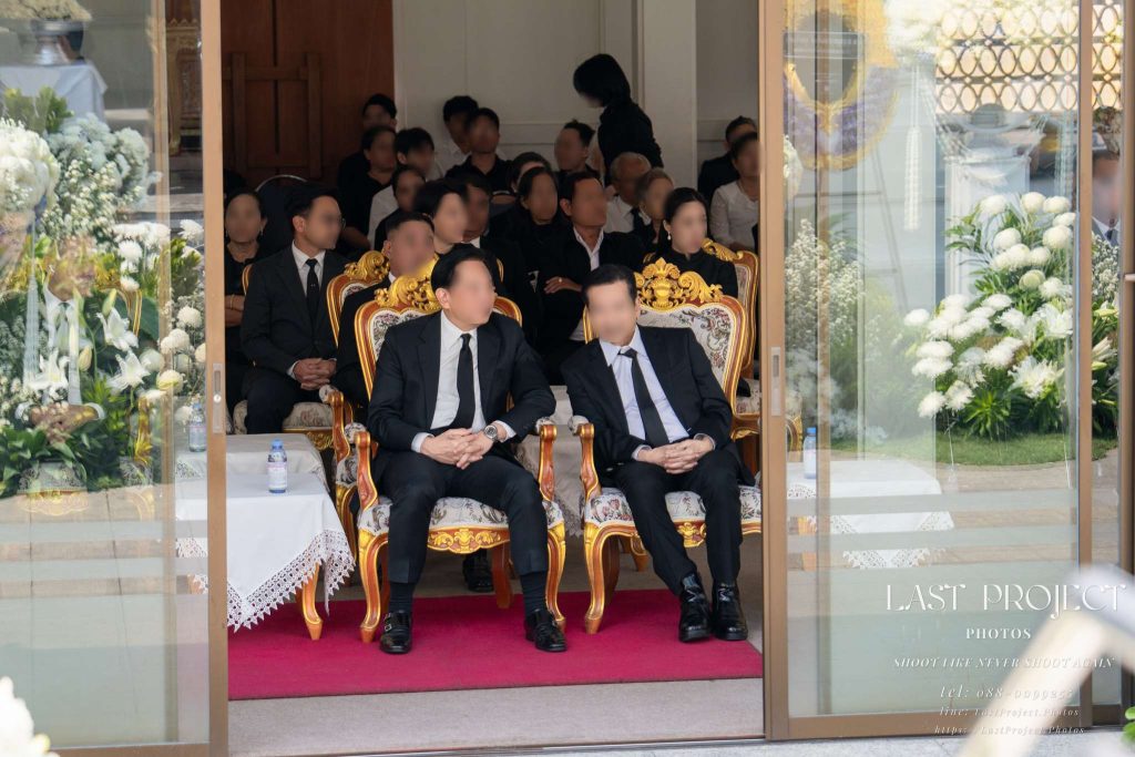ประธานและแขกผู้มีเกียรตินั่งรอร่วมพิธีฌาปนกิจศพ ณ ศาลาวัดไทย Presiding guests seated in the funeral pavilion during a Thai Buddhist cremation ceremony