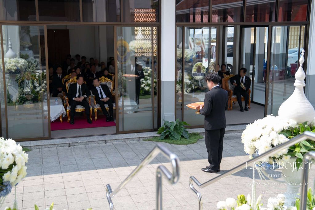 เจ้าภาพถือพานผ้าไตรบังสุกุลหน้าศาลาในพิธีฌาปนกิจศพ วัดเทพศิรินทร์ Host holding Buddhist robes on a tray during a Thai cremation ceremony at Wat Thepsirin