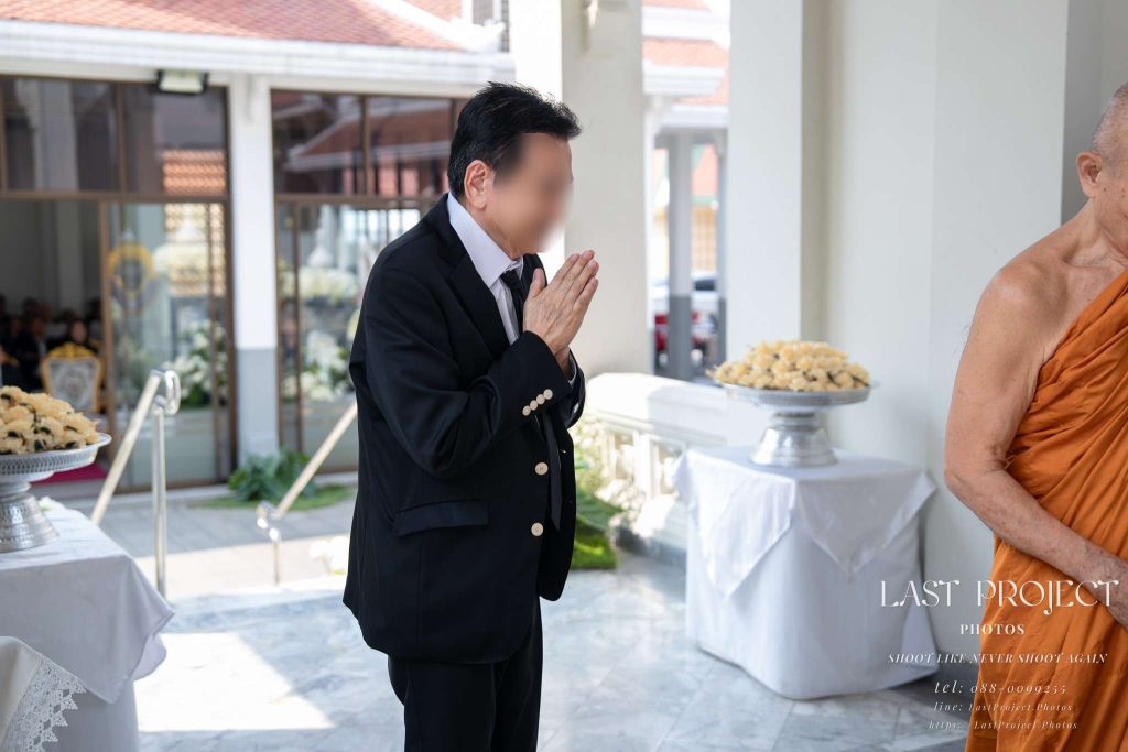 แขกผู้มีเกียรติพนมมือสำรวมหลังทอดผ้าไตรบังสุกุลในพิธีฌาปนกิจศพ A guest paying respect with palms pressed together after offering Bangsukula robes during a Thai funeral ceremony