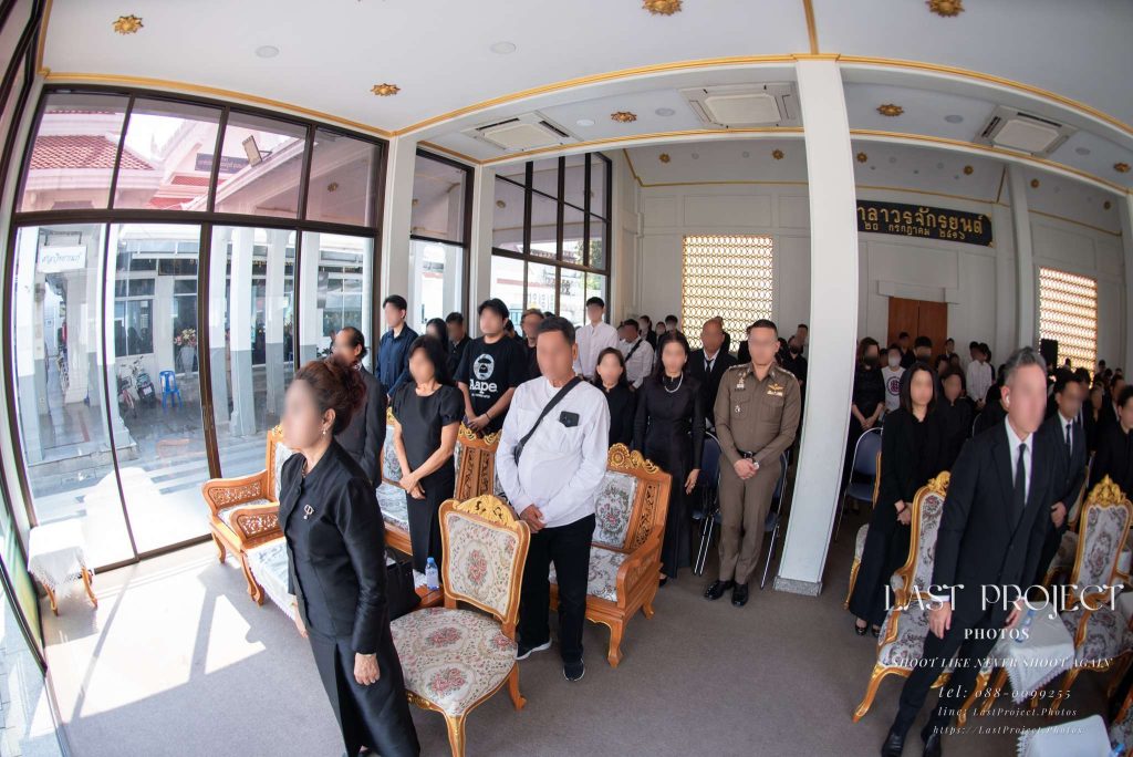 บรรยากาศแขกผู้มีเกียรติยืนสงบนิ่งไว้อาลัยภายในศาลาพิธีฌาปนกิจ วัดเทพศิรินทร์ Guests standing in a solemn moment of silence inside the pavilion during a Thai cremation ceremony at Wat Thepsirin