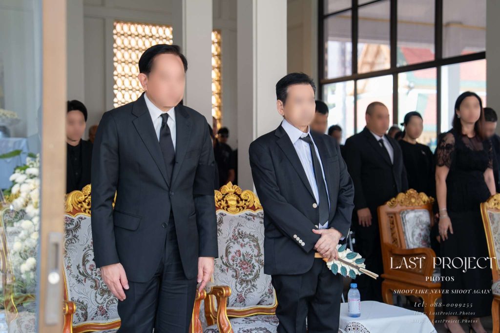 แขกผู้มีเกียรติยืนสงบนิ่งร่วมไว้อาลัยในพิธีฌาปนกิจศพ ณ เมรุวัดไทย VIP guests standing in a moment of silence at a Buddhist cremation ceremony in a Thai temple