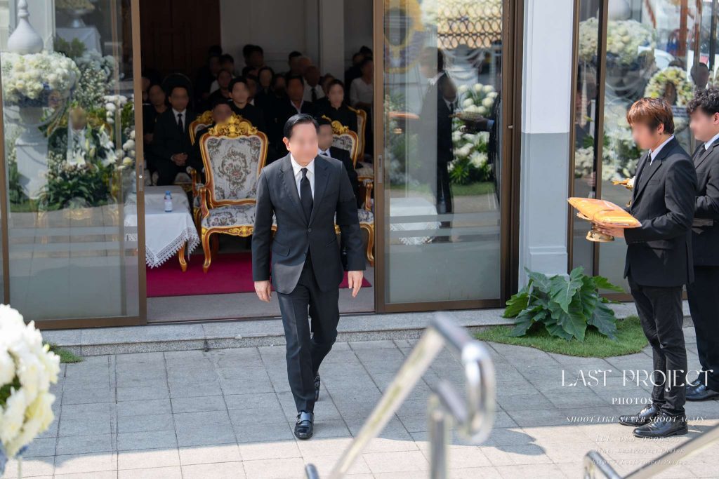 ประธานในพิธีกำลังเดินขึ้นสู่เมรุเพื่อทอดผ้าไตรบังสุกุลในพิธีฌาปนกิจศพ The guest of honor walking toward the crematorium to present the final Bangsukon robes during a Thai Buddhist cremation ceremony
