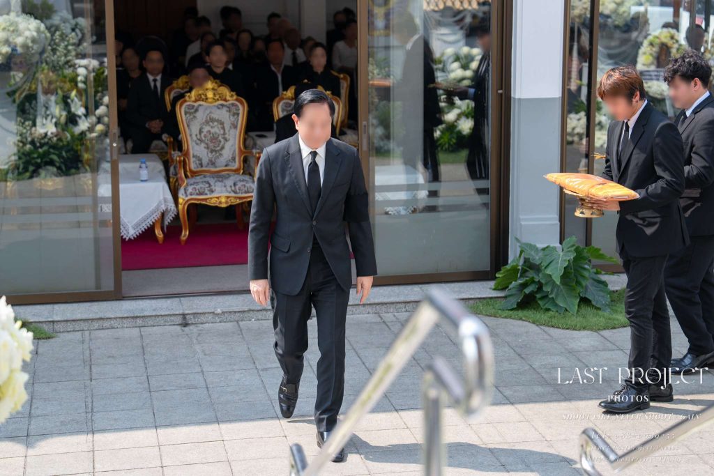 ช่างภาพถ่ายมุมสูงจากบนเมรุบันทึกภาพประธานในพิธีกำลังเดินขึ้นมาทอดผ้าไตรบังสุกุลในพิธีฌาปนกิจ High-angle shot from the crematorium capturing the presiding guest walking up to offer the Bangsukon robe at a Thai Buddhist cremation ceremony