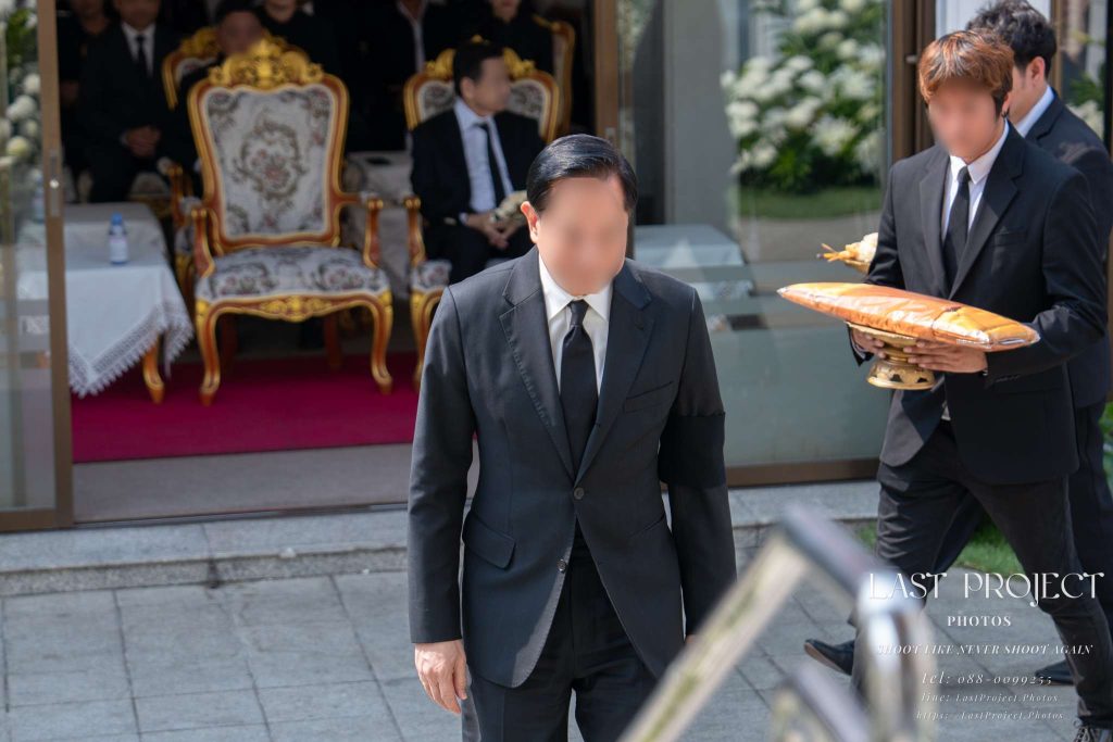 ประธานในพิธีเดินขึ้นทอดผ้าไตรบังสุกุลชุดสุดท้ายในพิธีฌาปนกิจ ณ เมรุวัดไทย Guest of honor walking to offer the final monk robe at a Thai Buddhist cremation ceremony