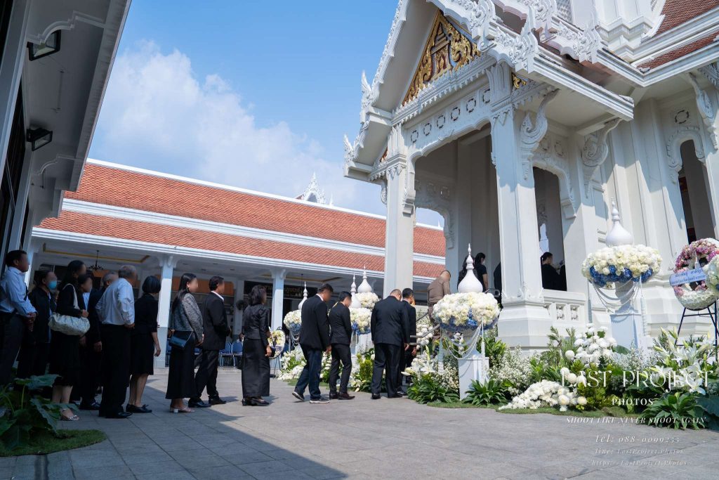 ภาพมุมกว้างแขกผู้มีเกียรติต่อแถวขึ้นเมรุเพื่อวางดอกไม้จันทน์ ณ วัดเทพศิรินทร์ Wide-angle view of mourners queuing to ascend the crematorium steps for the sandalwood flower placement at Wat Debsirin