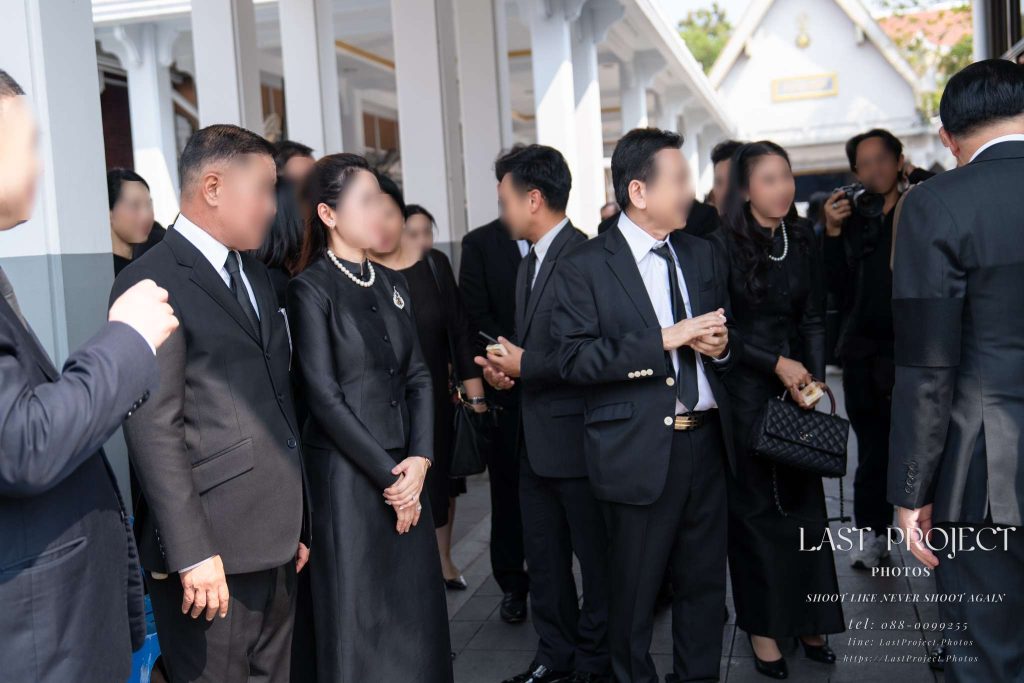ครอบครัวเจ้าภาพยืนส่งและกล่าวขอบคุณแขกผู้มีเกียรติบริเวณศาลาบำเพ็ญกุศลในพิธีฌาปนกิจศพ The host family seeing off and thanking attending guests outside the funeral pavilion during a Thai cremation ceremony