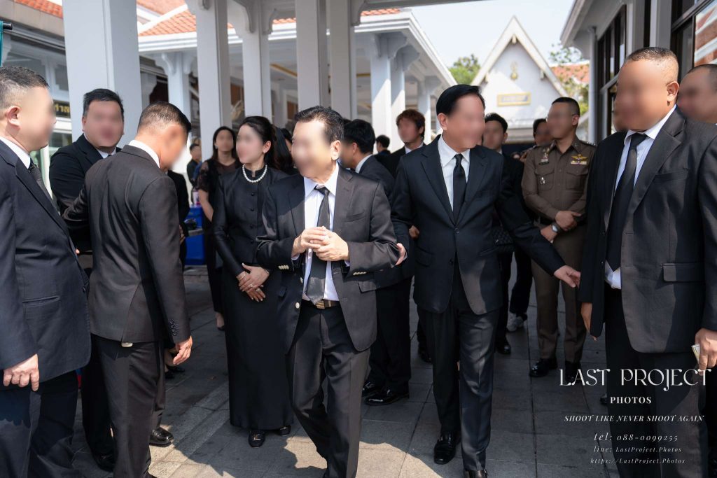 ครอบครัวเจ้าภาพยืนส่งแขกคนสำคัญเดินทางกลับหลังเสร็จพิธีฌาปนกิจศพ ณ วัดไทย Host family seeing off VIP guests departing after the cremation ceremony at a Thai temple