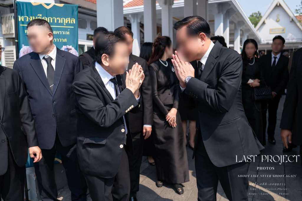 แขกผู้มีเกียรติยกมือไหว้ทักทายกันอย่างอบอุ่นหลังเสร็จพิธีฌาปนกิจศพ ณ วัดไทย Distinguished guests greeting each other with a traditional Thai wai after the cremation ceremony at a temple