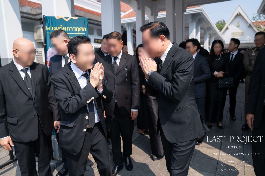 แขกผู้มีเกียรติยกมือไหว้ร่ำลากันอย่างอบอุ่นหลังเสร็จสิ้นพิธีวางดอกไม้จันทน์ในงานฌาปนกิจศพ Distinguished guests exchanging respectful Thai wais while bidding farewell after the cremation ceremony at a temple