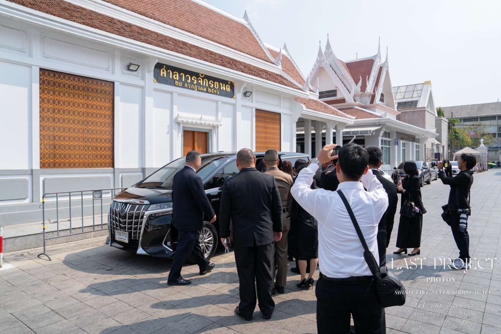เจ้าภาพเดินส่งแขกผู้ใหญ่คนสำคัญถึงที่รถตู้บริเวณหน้าศาลาในพิธีฌาปนกิจศพ ณ วัดไทย Host family escorting a distinguished VIP guest to their car outside the temple pavilion after the Thai cremation ceremony